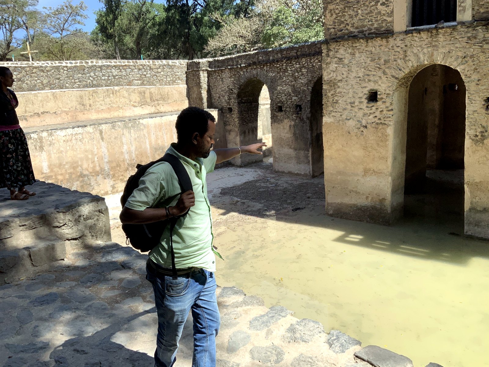 Local guide explaining route context beside a Gondar water castle.